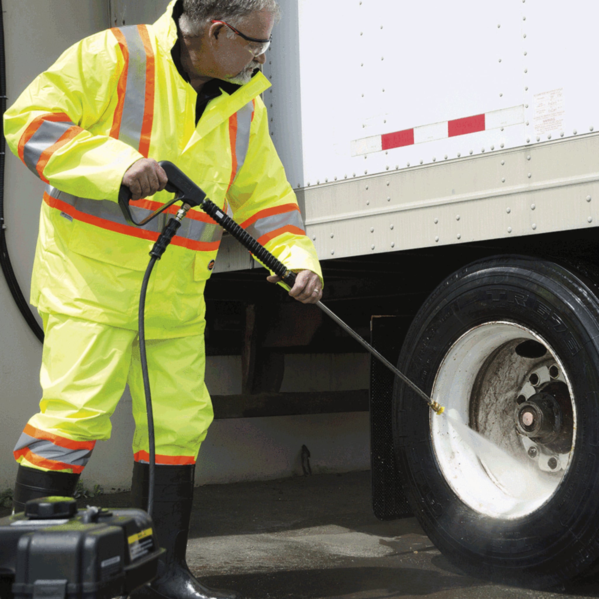 Worker using power washer wearing yellow hi-vis rain suit